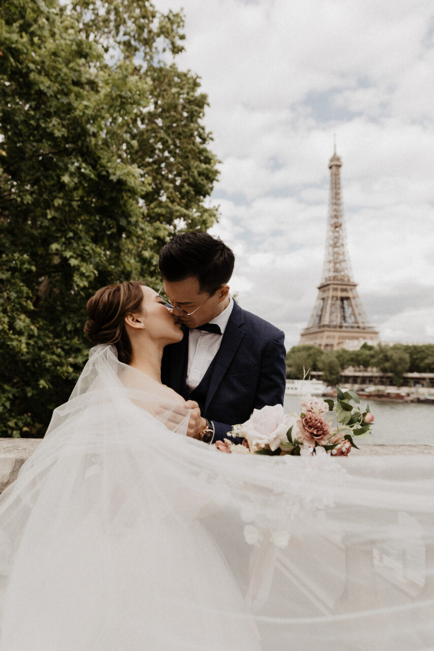 Bride and groom kissing on Bir Hakeim bridge with Eiffel tower