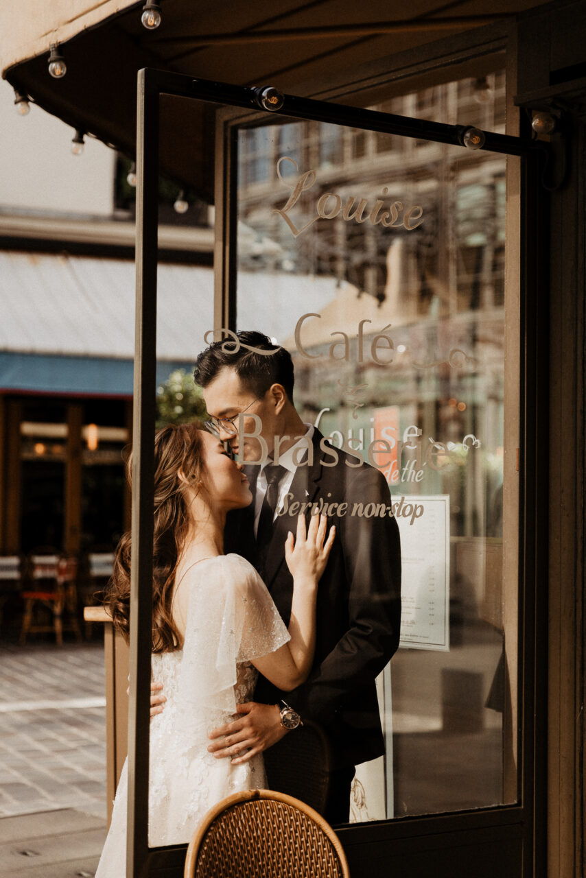 Bride and groom through the glass at a Paris cafe