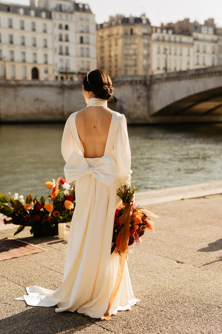 Bride in wedding dress with open back by the Seine river Paris