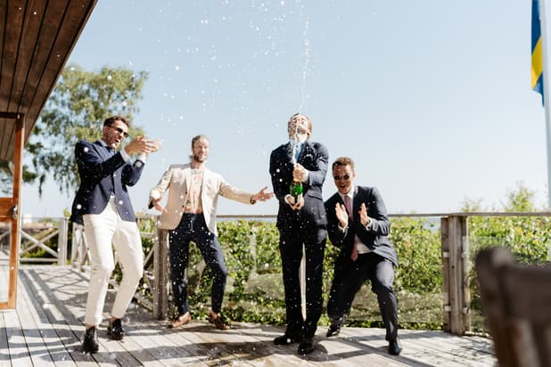 Champagne popping Celebration groomsmen wedding day photos