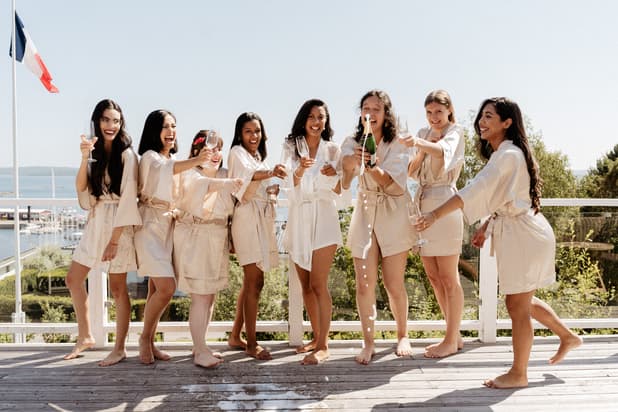 Bride celebrating & popping champagne with Bridesmaids in bridal robes