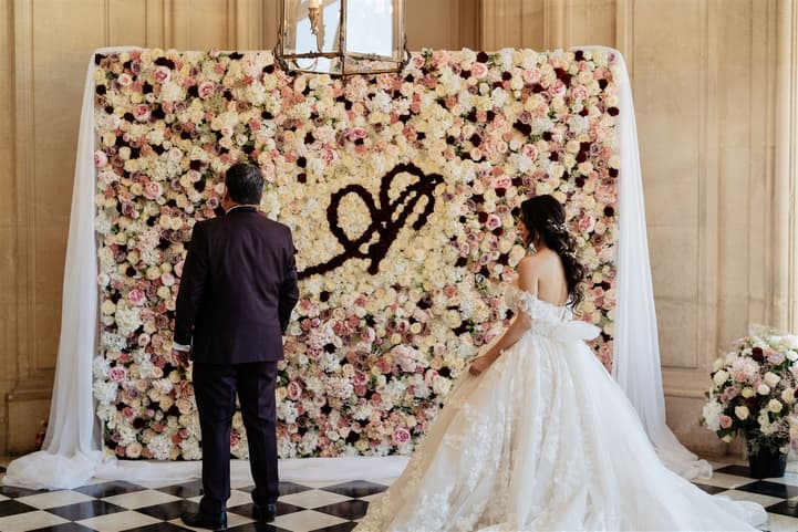 The bride’s first look with her father in front of the rose wall, her off-shoulder lace ball gown and cathedral veil