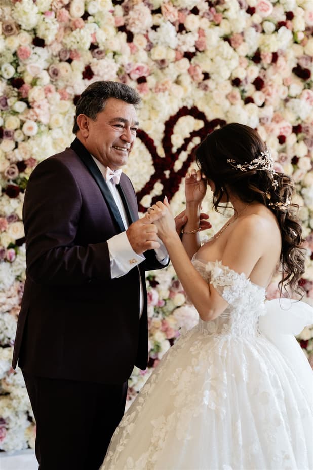The bride and her father holding hands at the first look, neither of them able to speak