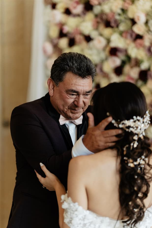 The bride’s father holding her face at the first look, a pearl and crystal comb in her curls before the wedding