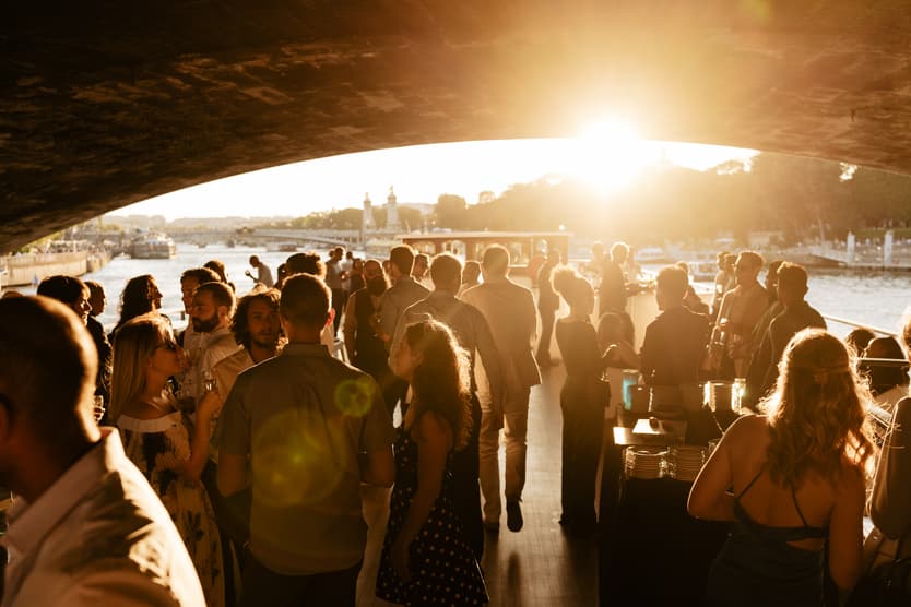 Guests at the welcome dinner filling the deck as the sun goes down over the Seine