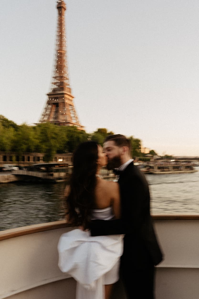 Bride and groom kissing on the boat as it passes the Eiffel Tower