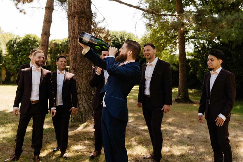 Champagne sprayed on the castle grounds, the groomsmen in burgundy and navy suits