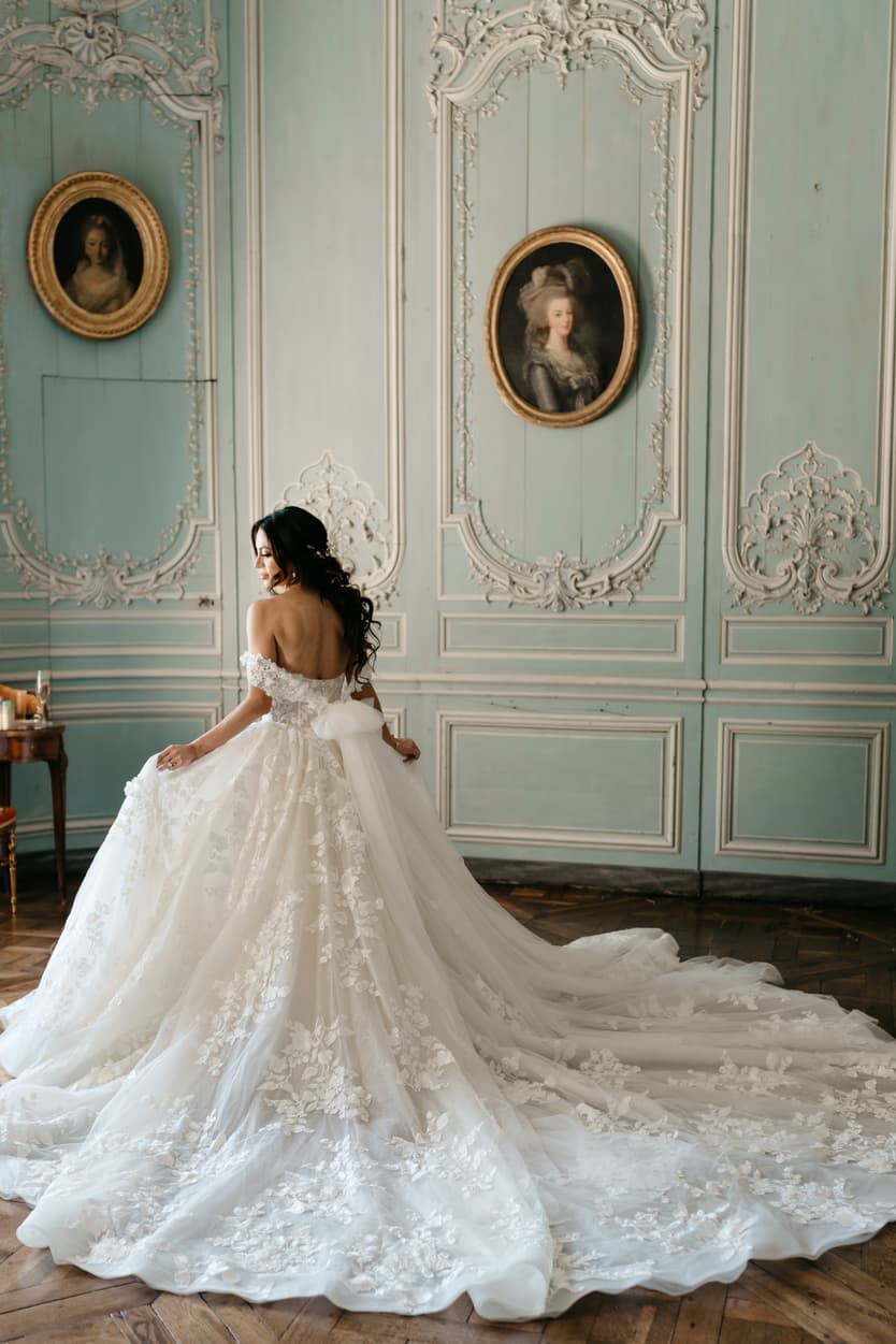 The cathedral train of the lace wedding dress spread across the parquet of the boiserie salon