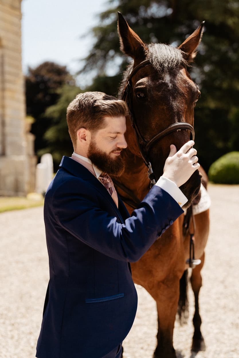 The groom with the horse at the front of the château, in his blue suit and bow tie
