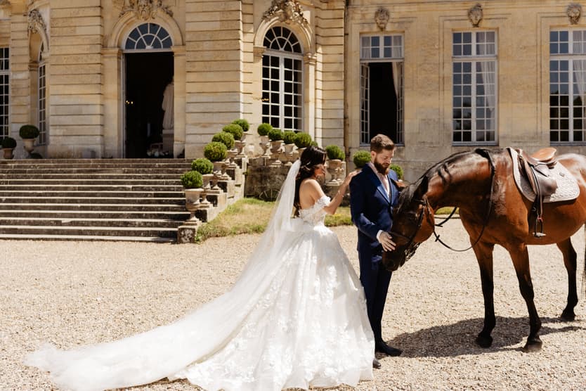 Bride and groom meeting at the horse on the gravel court of the château