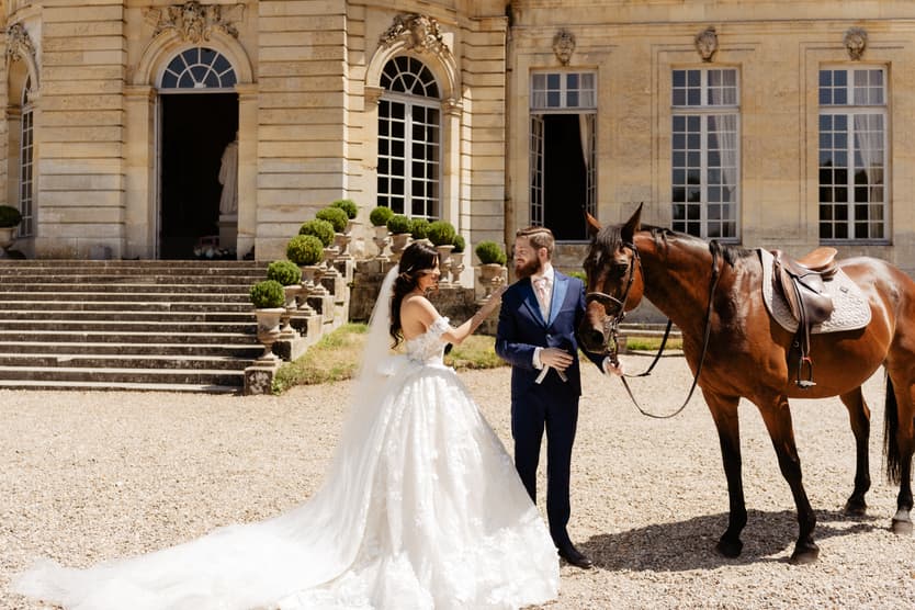 The couple holding the horse’s reins together at their first look, the château behind them