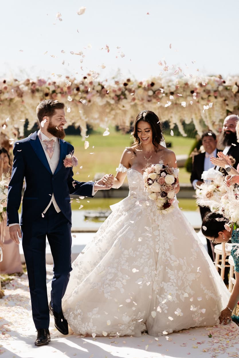 The newly married couple coming back up the aisle under a shower of petals