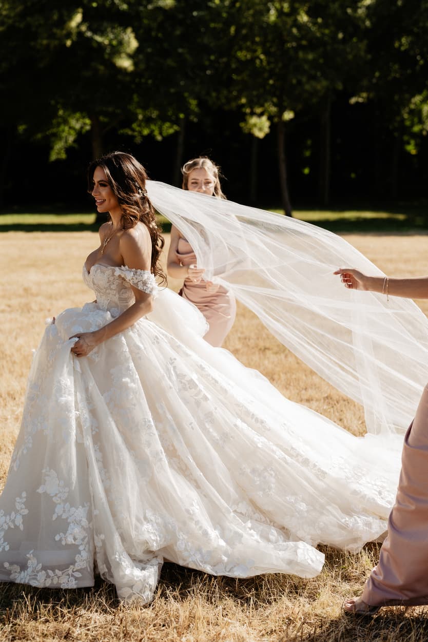 Bridesmaids lifting the bride’s cathedral veil in the park of the château