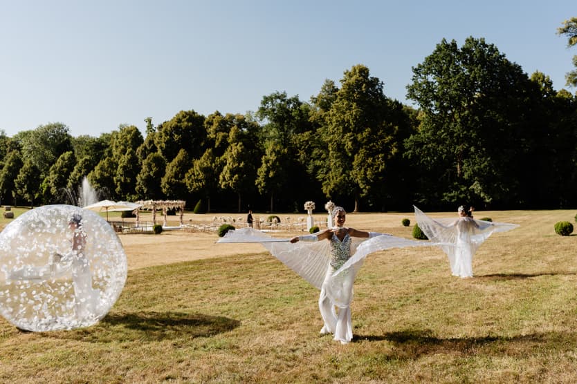 Two giant transparent balls with dancers inside rolling across the château lawn