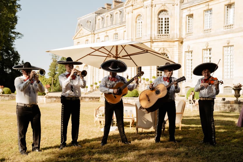 The mariachi band under a parasol at the wedding cocktail hour, the château behind them