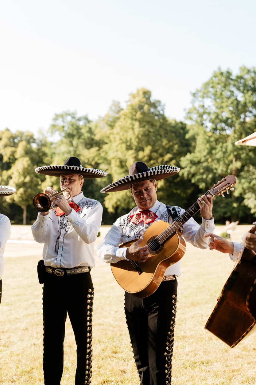 The mariachi band playing on the château lawn in sombreros and white shirts