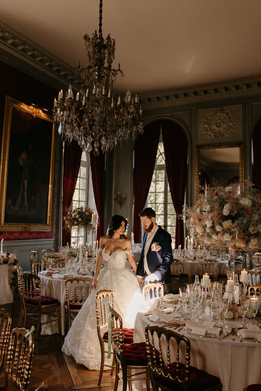 A round table of the wedding reception, gold Napoleon chairs on burgundy velvet
