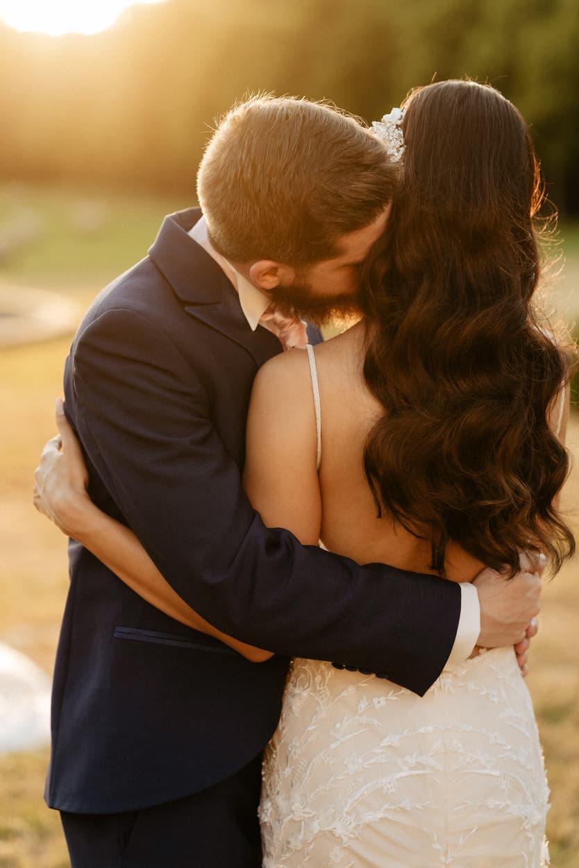The couple in the last of the sun, his hand at her back, the trees of the château park behind