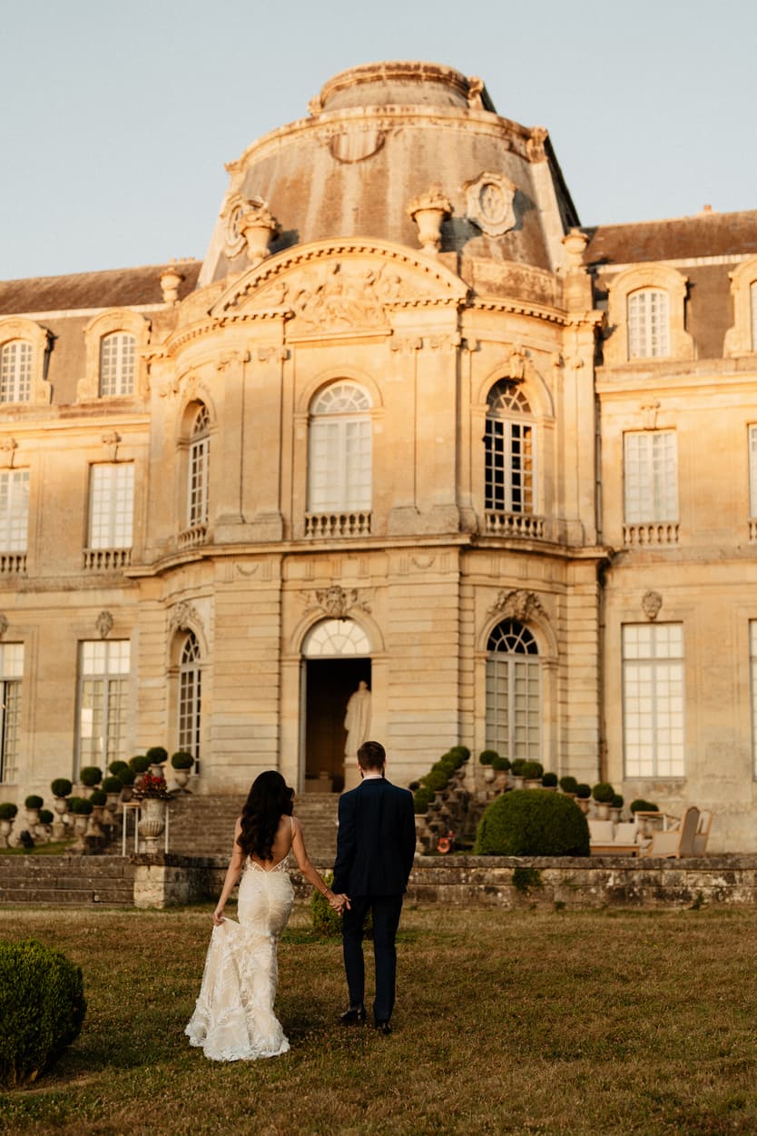 The bride in her fitted lace evening gown at a window of the château, in black and white