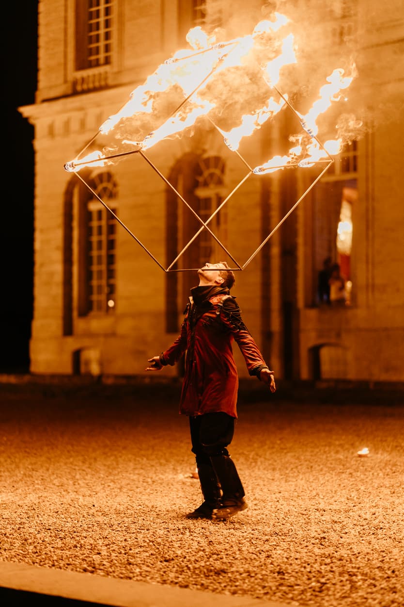 Fire show at the château wedding, the performer spinning a burning frame before the guests