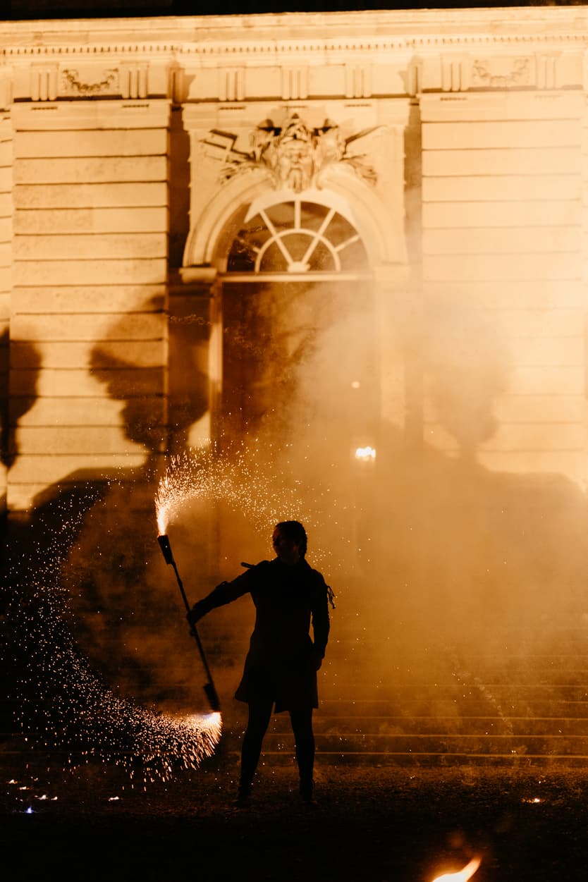 The fire performer in silhouette against the château, sparks falling around him
