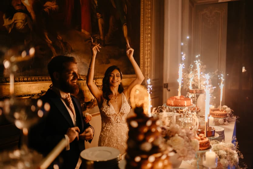 Sparklers over the wedding cake and the dessert table in the château salon