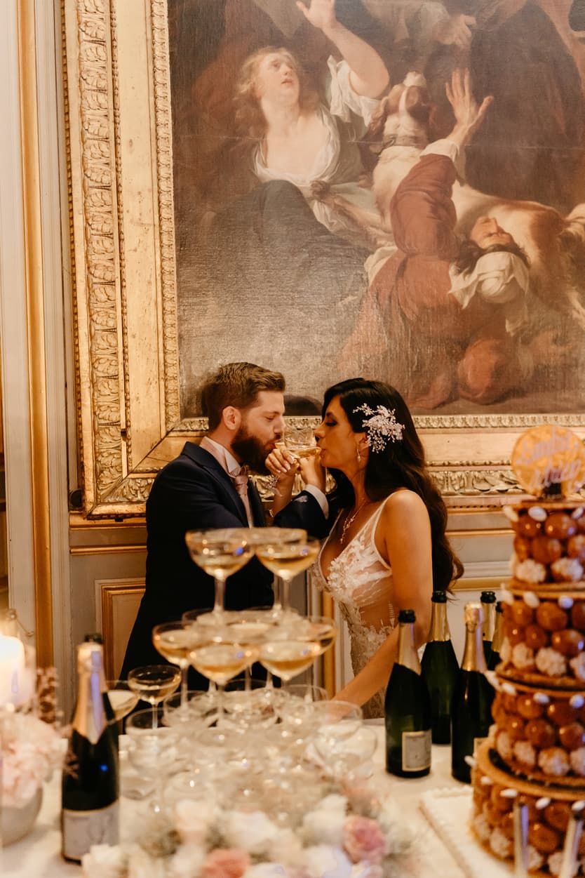 The couple at the dessert table with the champagne tower and the croquembouche
