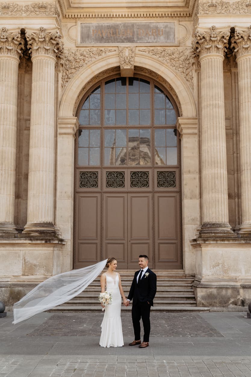 groom and bride walking hand in hand at Louvre