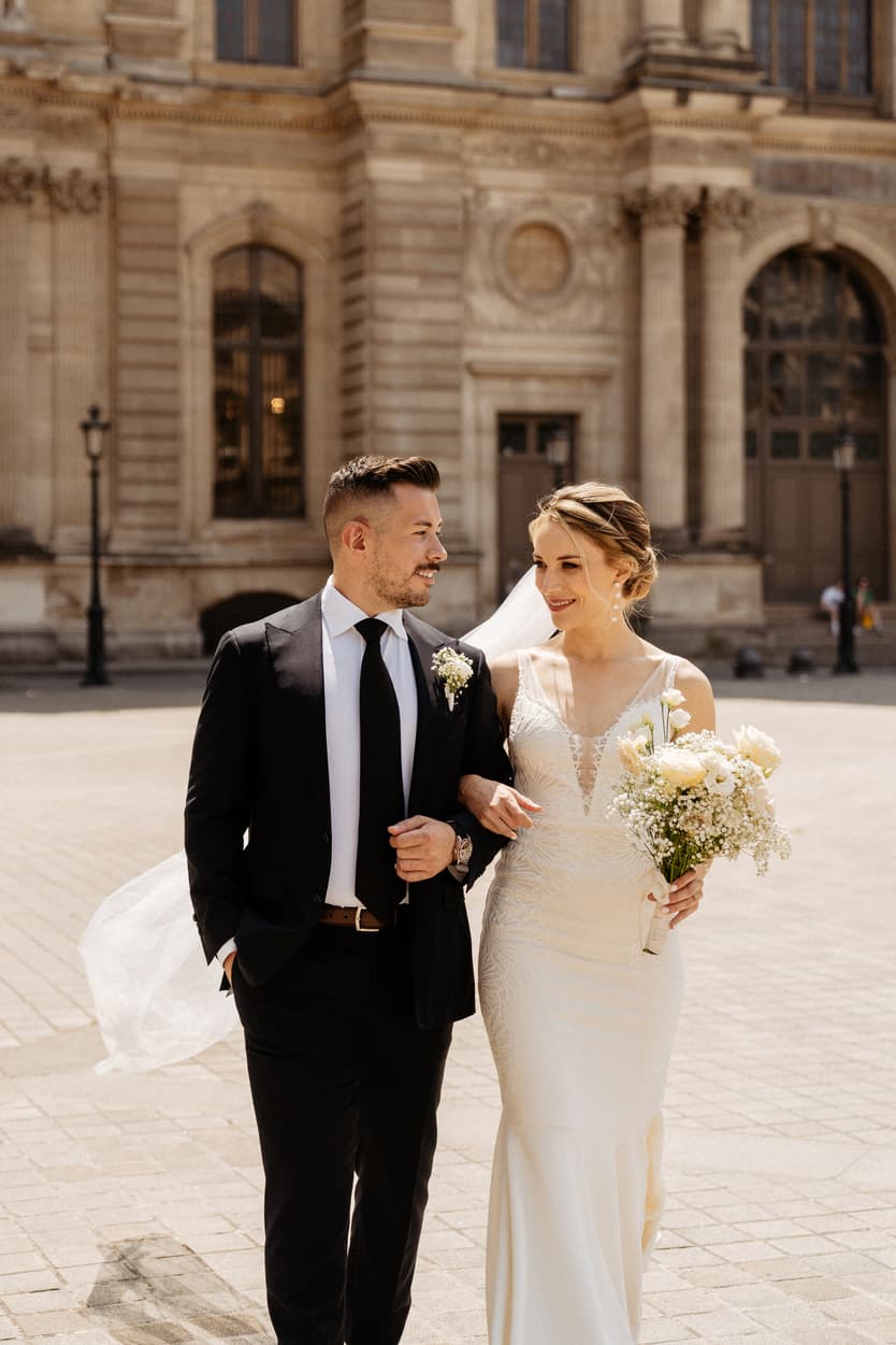 groom and bride walking hand in hand at Louvre