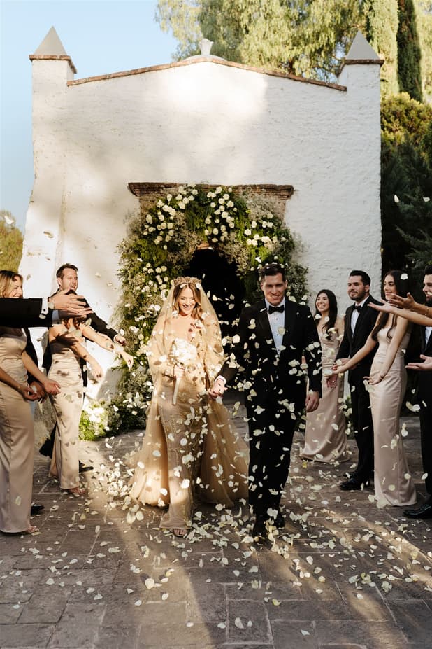 Groom and Bride do entrance to cocktail party under a petals rain confetti