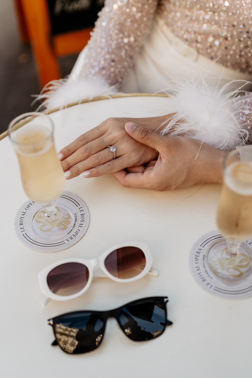 paris pre-wedding couple photoshoot at a red cafe bride wearing cool glasses drinking champagne