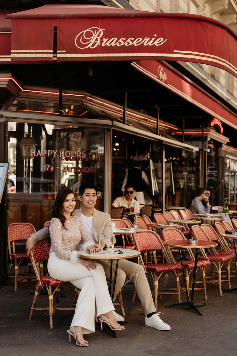 paris pre-wedding couple photoshoot at a red cafe bride wearing cool glasses drinking champagne
