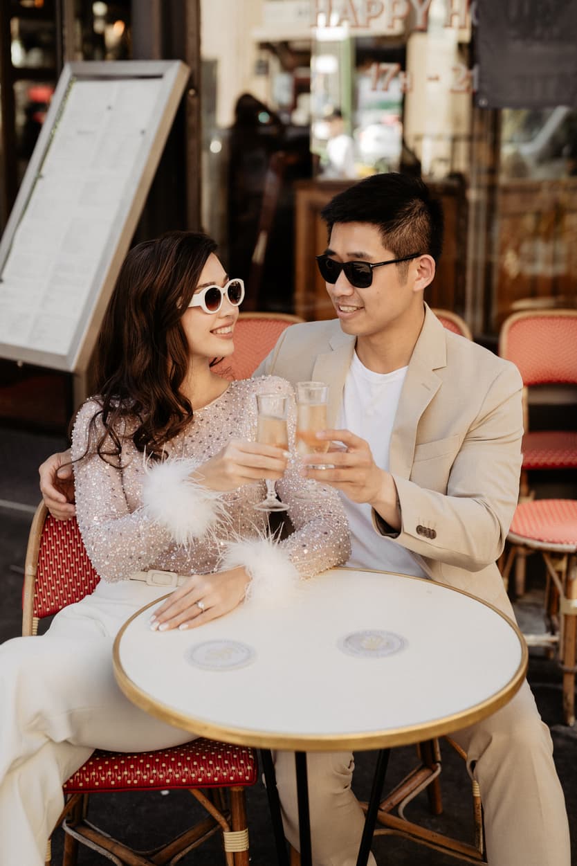 paris pre-wedding couple photoshoot at a red cafe bride wearing cool glasses drinking champagne