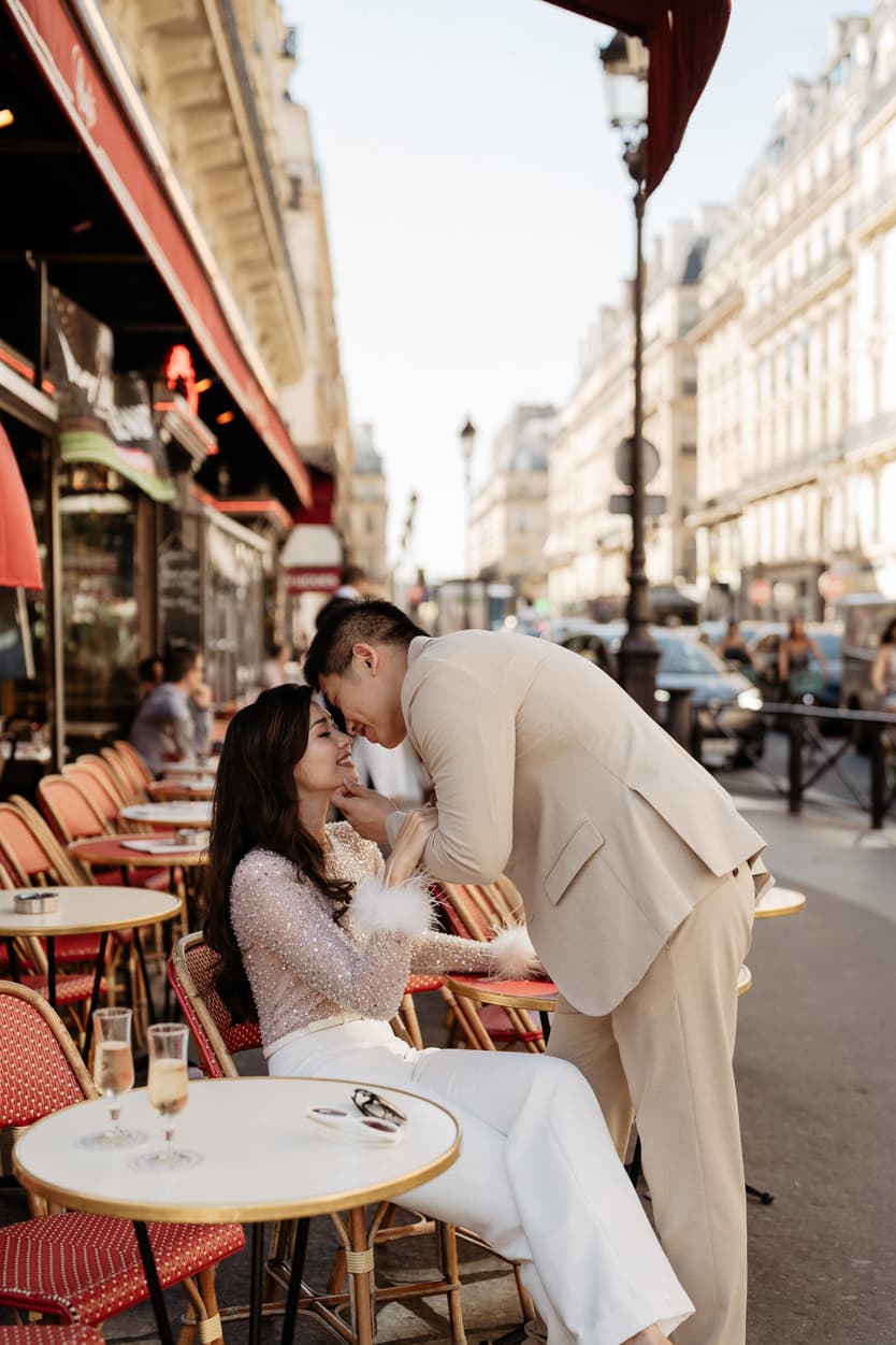 paris pre-wedding couple photoshoot at a red cafe bride wearing cool glasses drinking champagne