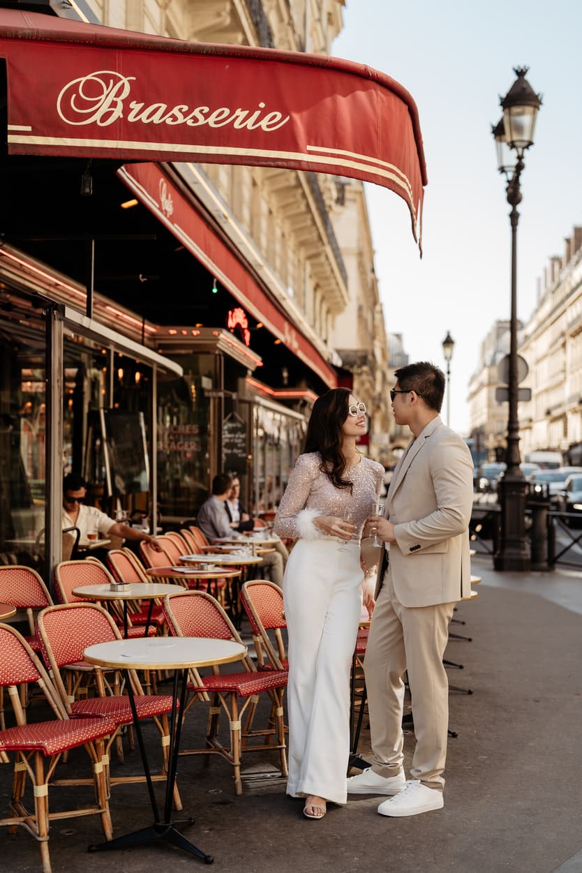 paris pre-wedding couple photoshoot at a red cafe bride wearing cool glasses drinking champagne