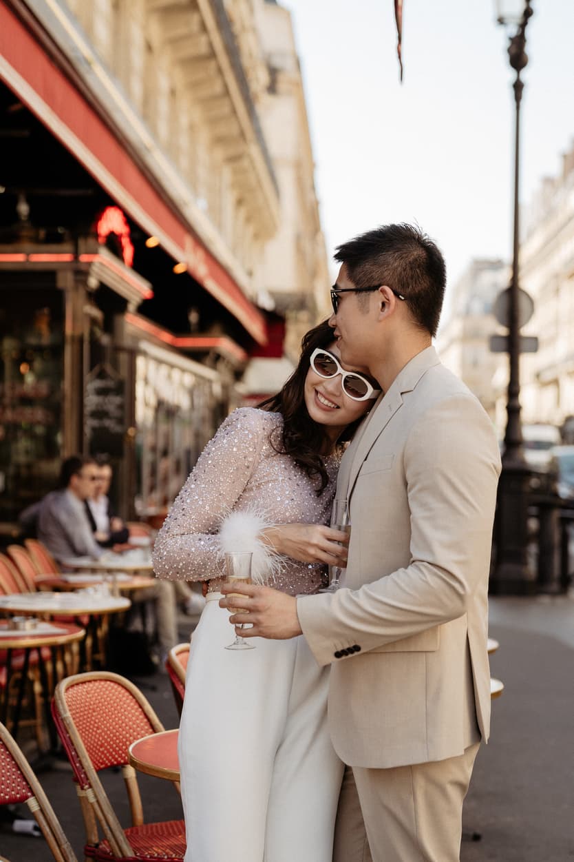 paris pre-wedding couple photoshoot at a red cafe bride wearing cool glasses drinking champagne