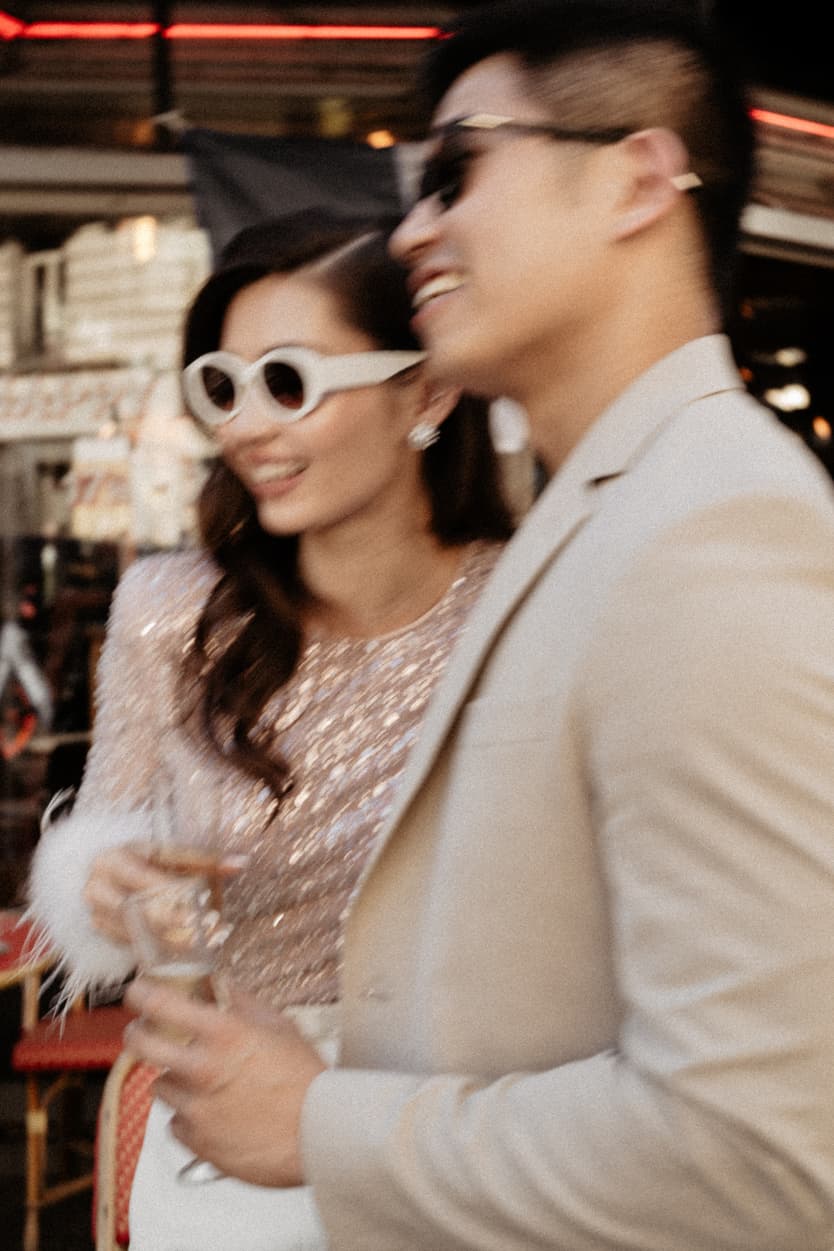 paris pre-wedding couple photoshoot at a red cafe bride wearing cool glasses drinking champagne