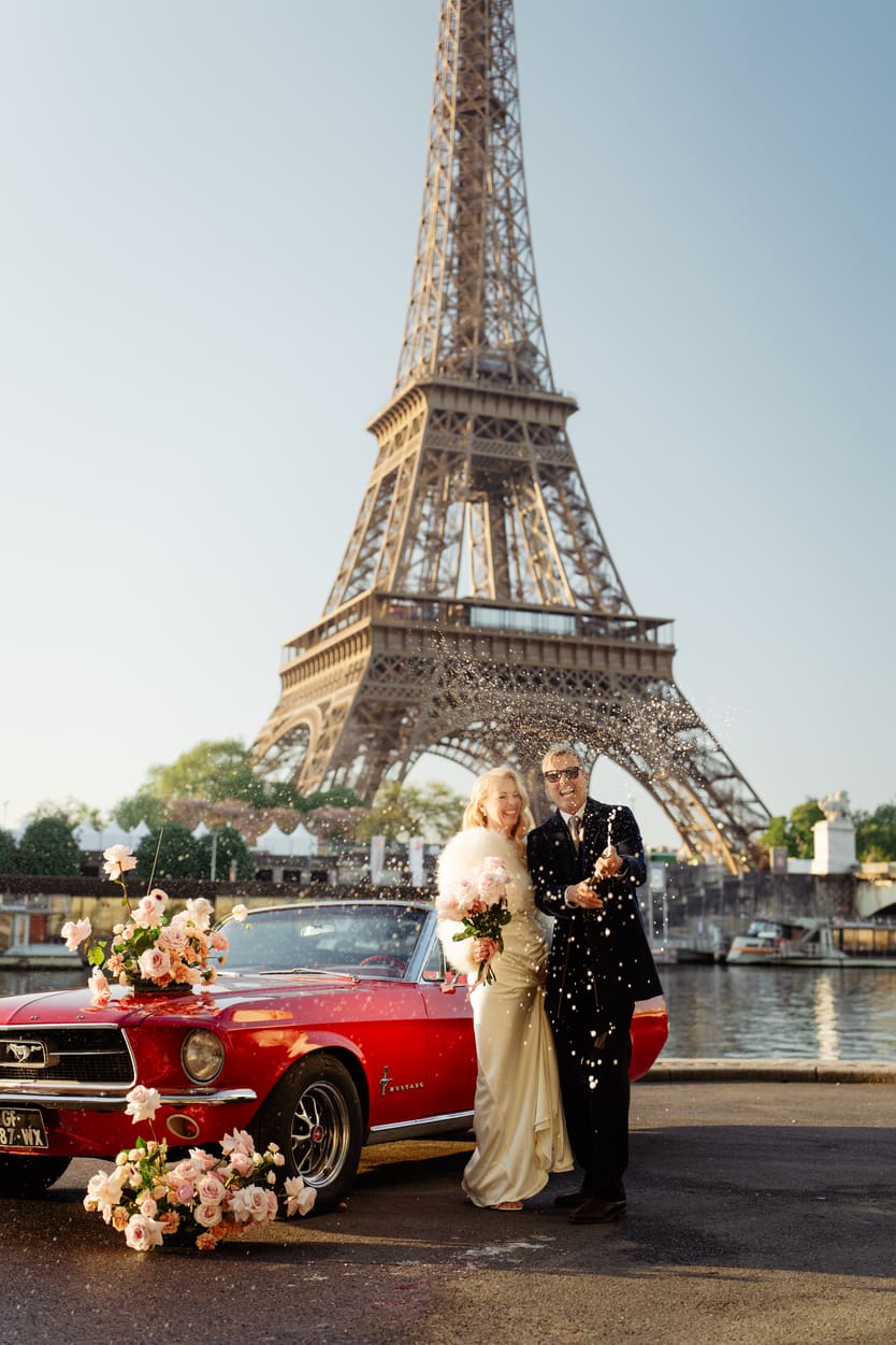 couple popping champagne in front of eiffel tower for their elopement