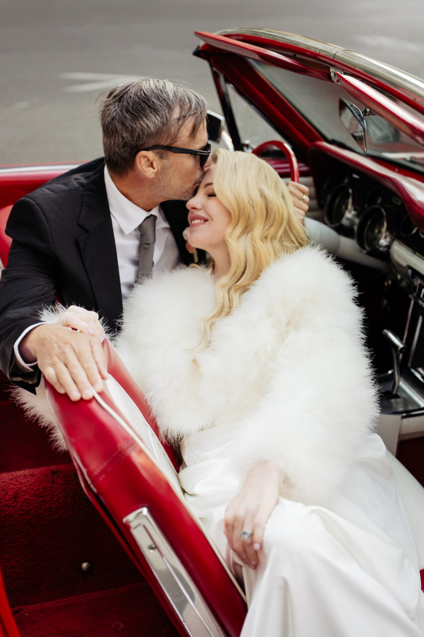 Bride and groom kissing forehead in a vintage mustang car in an old hollywood elopement in Paris