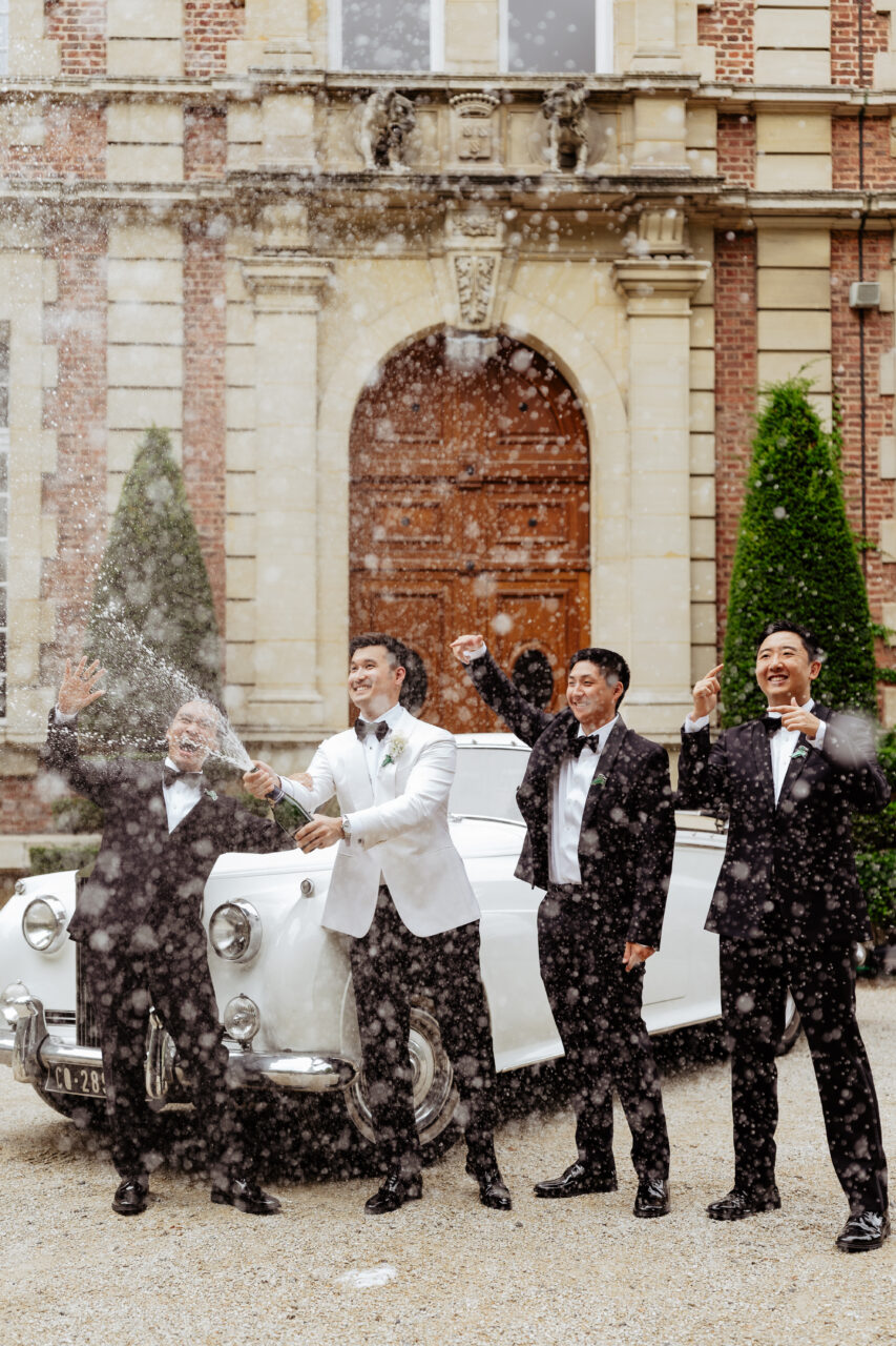 Groomsmen at French destination wedding in Château Bouffémont popping champagne