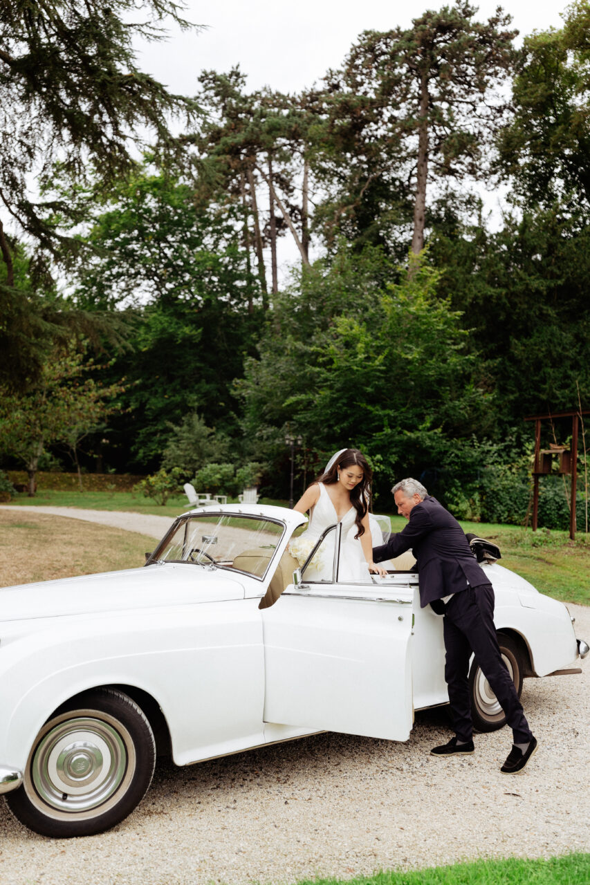 Bride and a white vintage car at Château Bouffémont
