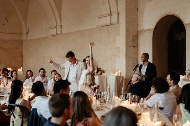 The couple on their feet for the speeches at the candlelit welcome dinner in the orangerie, guests applauding