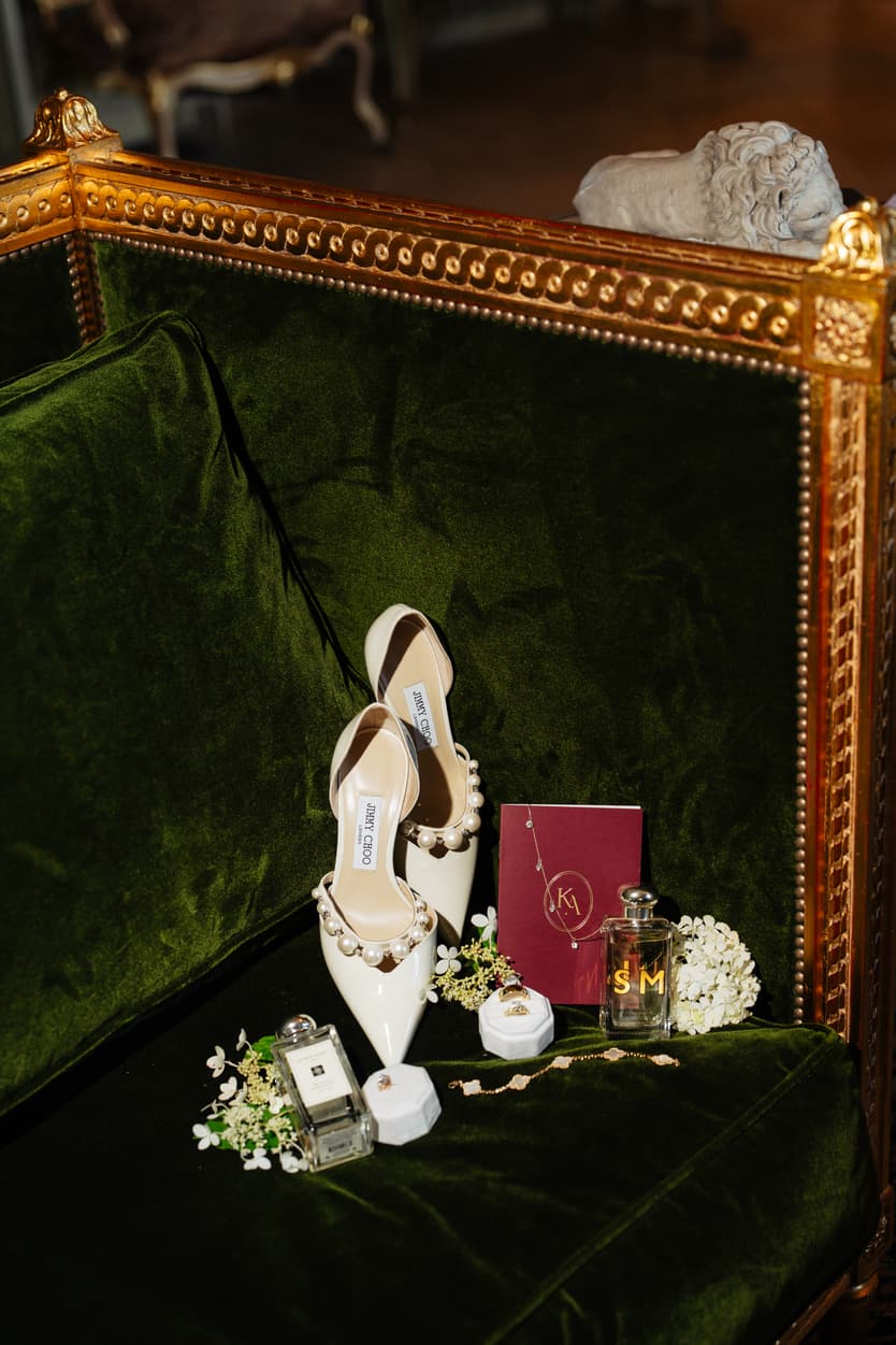 Jimmy Choo wedding shoes, perfume and the rings on green velvet at Château du Grand Lucé, a gold monogrammed card