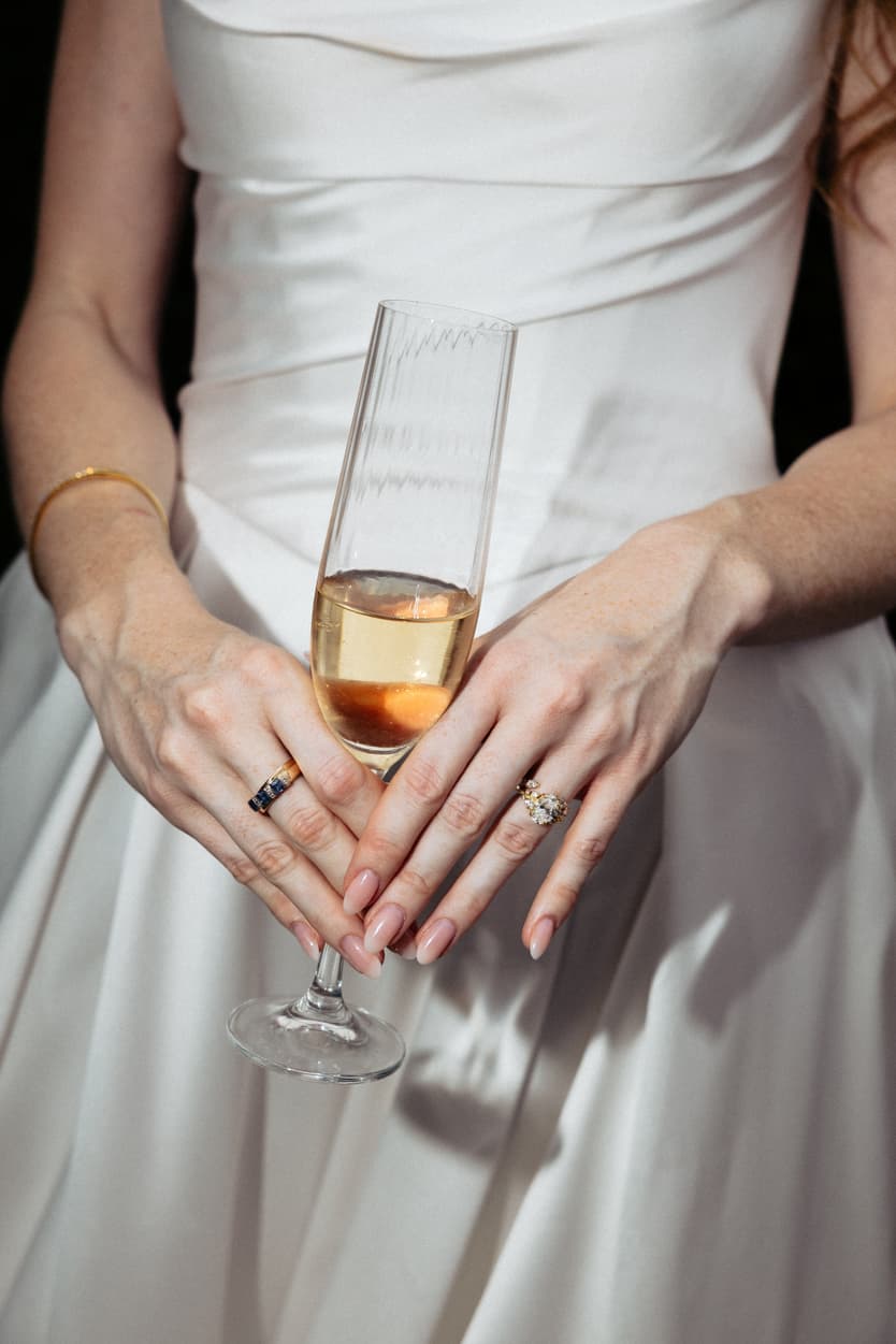 The bride’s hands and her wedding ring around a coupe of champagne at the château dinner