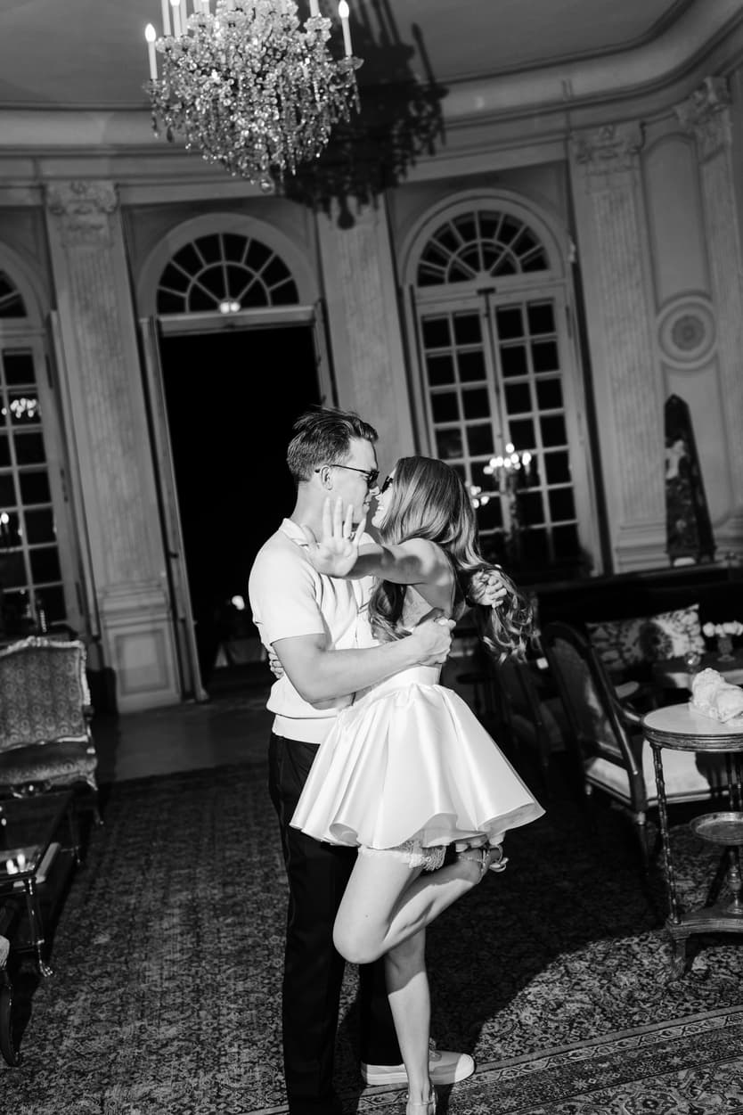 The groom lifting the bride in her short white party dress, in black and white