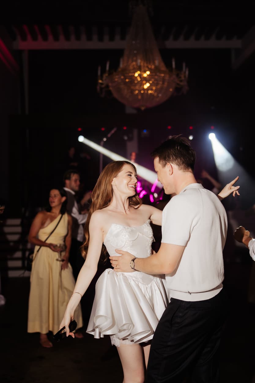 The couple dancing under the crystal chandelier, her short satin second dress swinging in the spotlights