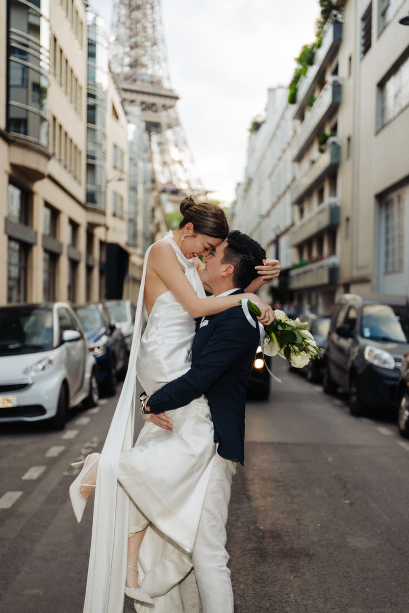 groom lifting bride on Eiffel tower street for their prewedding photos