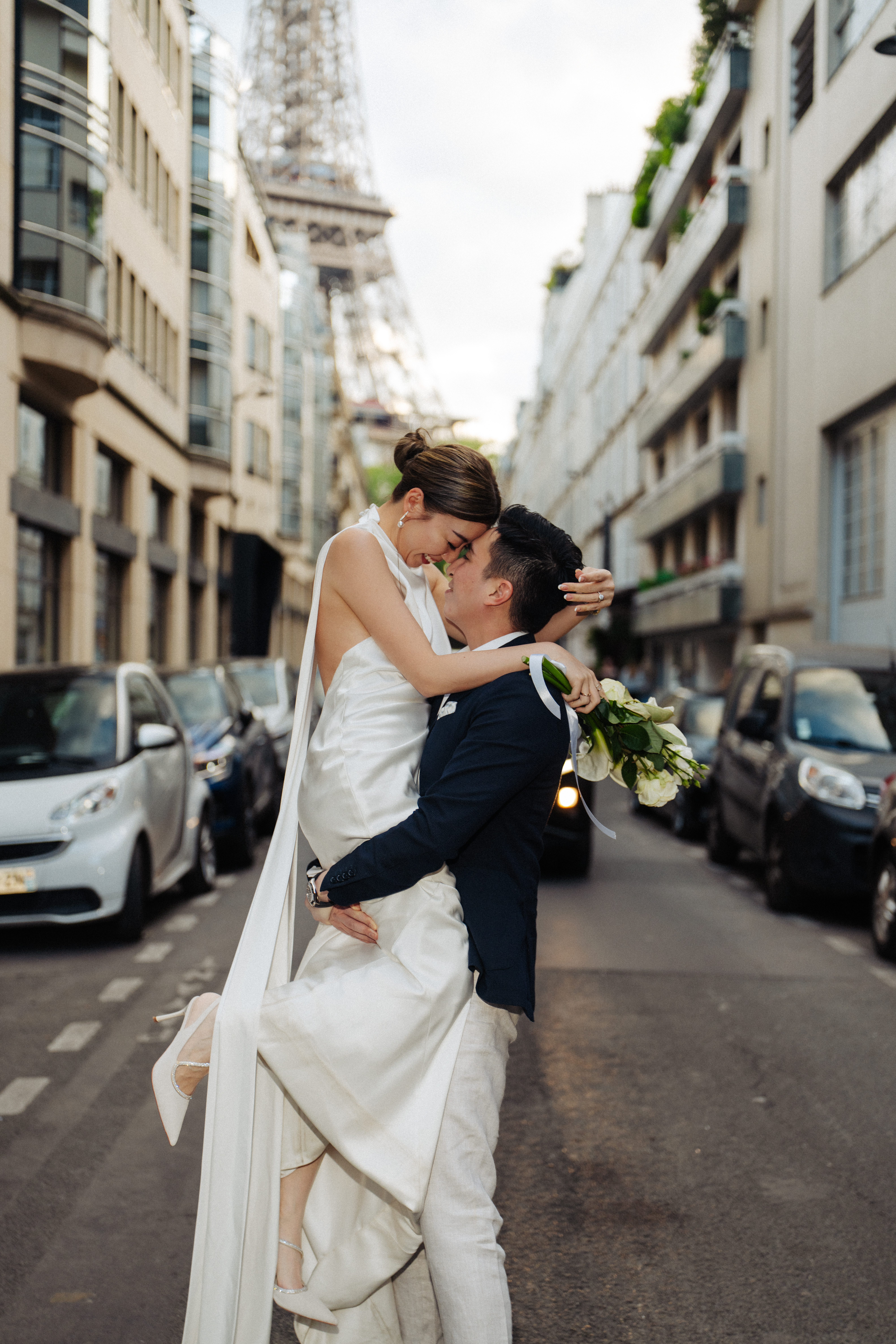 groom lifting bride on Eiffel tower street for their prewedding photos