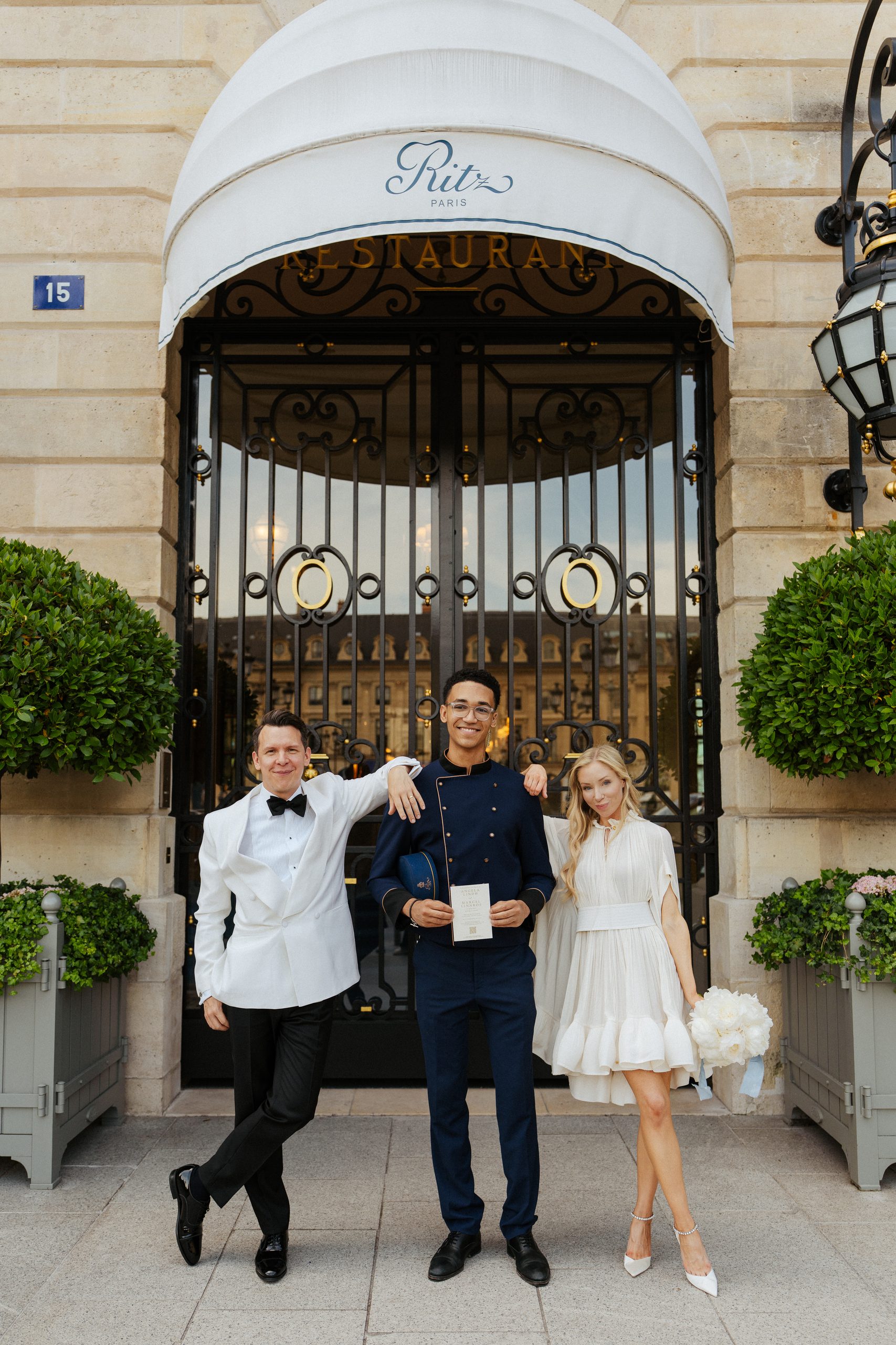 the ritz summer wedding, couple standing in front of Ritz hotel Paris facade with the bellboy