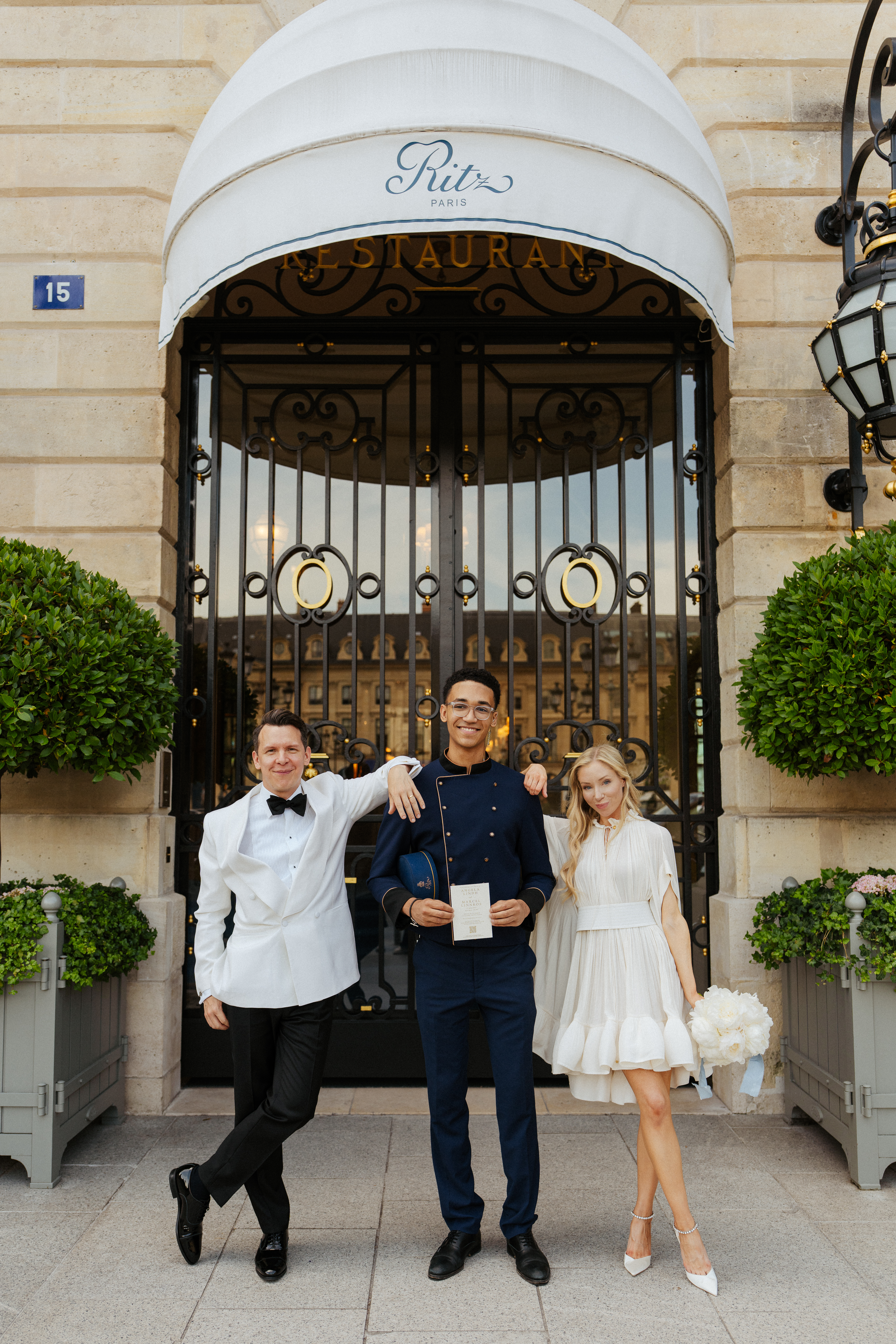 the ritz summer wedding, couple standing in front of Ritz hotel Paris facade with the bellboy
